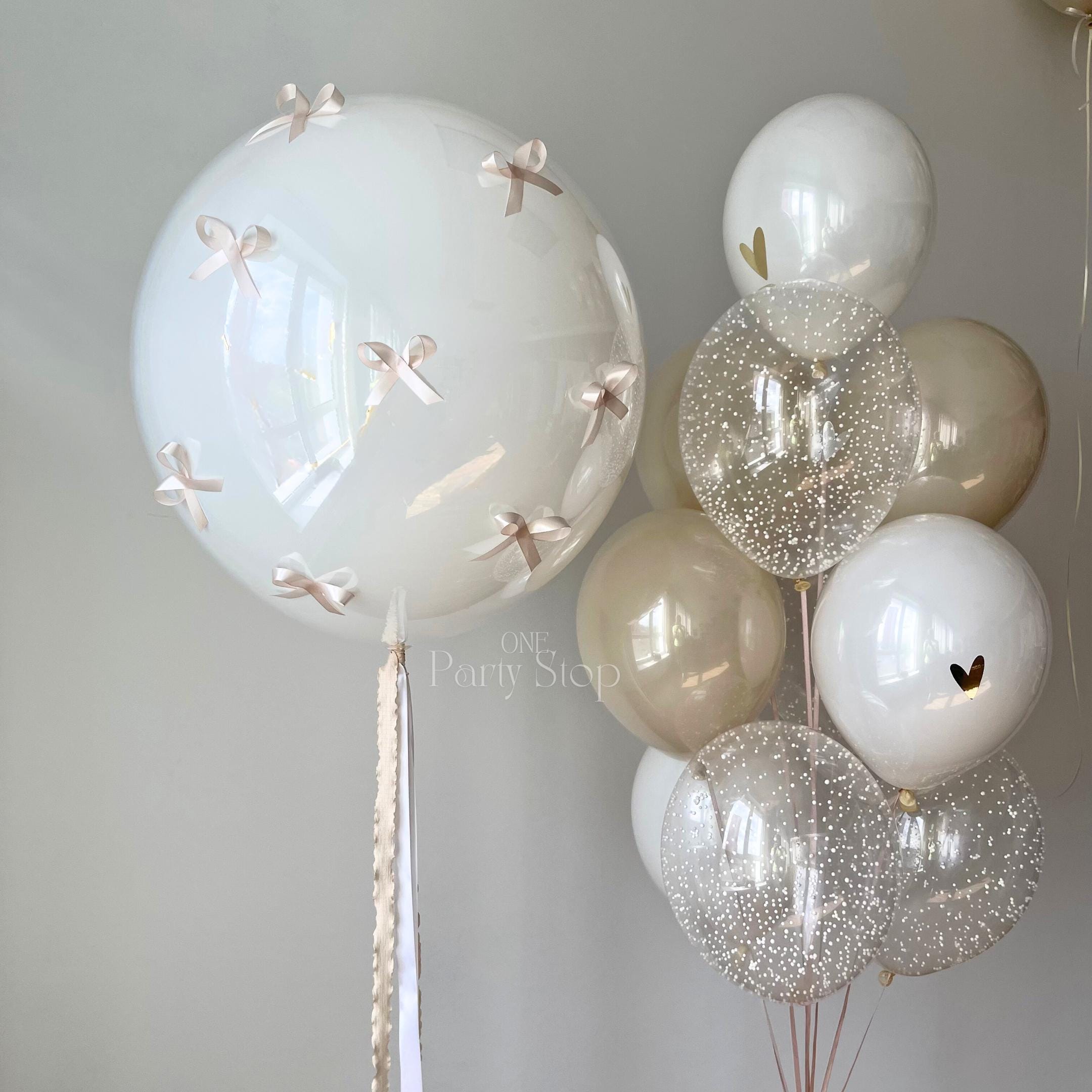 Luxury neutral balloon bouquet with giant white balloon and satin bows.
DIY coquette balloon bouquet kit for elegant birthdays and baby showers.
Giant 24-inch white balloon with neutral champagne and confetti balloons.
Pinterest-inspired luxury balloon decoration for modern celebrations.
Elegant neutral party balloon arrangement with bows and heart details.